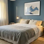 Chambre cocooning avec mur bleu poudré, tableau scandinave abstrait et linge de lit blanc
